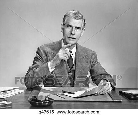 1950s SENIOR GRAY HAIRED BUSINESS EXECUTIVE WITH MUSTACHE SEATED AT DESK HOLDING PAPER GESTURING WITH FINGER LOOKING AT CAMERA View Large Photo Image Stock Photography - 1950s SENIOR GRAY HAIRED BUSINESS EXECUTIVE WITH MUSTACHE SEATED AT DESK HOLDING PAPER GESTURING WITH FINGER LOOKING AT CAMERA. Fotosearch