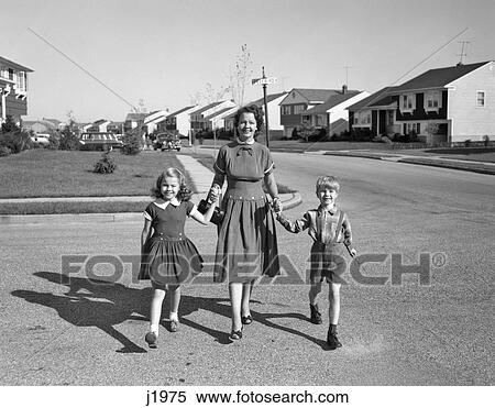 1950S Smiling Happy Mother Holding Hands Son And Daughter Walking Across Suburban Housing Development Street Looking At Camera View Large Photo Image Stock Photography - 1950S Smiling Happy Mother Holding Hands Son And Daughter Walking Across Suburban Housing Development Street Looking At Camera . Fotosearch