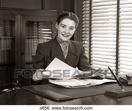 1950s SMILING WOMAN BUSINESS EXECUTIVE AT DESK HOLDING PAPERS LOOKING AT CAMERA View Large Photo Image Stock Photograph - 1950s SMILING WOMAN BUSINESS EXECUTIVE AT DESK HOLDING PAPERS LOOKING AT CAMERA. Fotosearch