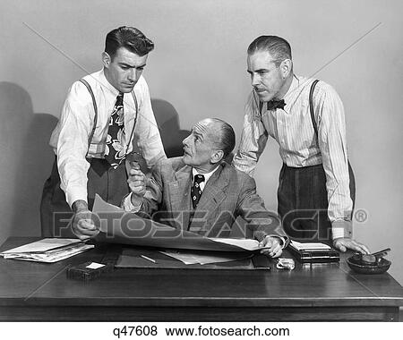 1950s THREE BUSINESS MEN IN OFFICE STRATEGY CONFERENCE TWO STANDING ONE SEATED LOOKING AT PAPERS AND PLANS View Large Photo Image Stock Photo - 1950s THREE BUSINESS MEN IN OFFICE STRATEGY CONFERENCE TWO STANDING ONE SEATED LOOKING AT PAPERS AND PLANS. Fotosearch