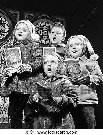 Stock Image - 1950s TWO GIRLS TWO BOYS SINGING CHRISTMAS CAROLS. Fotosearch