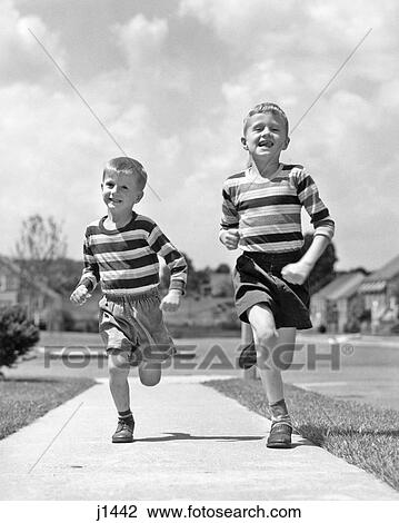 1950s TWO SMILING BOYS BROTHERS WEARING STRIPED SHIRTS SHORTS RUNNING ON SIDEWALK LOOKING AT CAMERA SUBURBAN NEIGHBORHOOD View Large Photo Image Stock Image - 1950s TWO SMILING BOYS BROTHERS WEARING STRIPED SHIRTS SHORTS RUNNING ON SIDEWALK LOOKING AT CAMERA SUBURBAN NEIGHBORHOOD. Fotosearch
