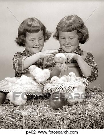 1950s TWO TWIN GIRLS PLAYING WITH BABY CHICKS TWINS PAIR STRAW BALE HATS APPLE View Large Photo Image Stock Image - 1950s TWO TWIN GIRLS PLAYING WITH BABY CHICKS TWINS PAIR STRAW BALE HATS APPLE. Fotosearch