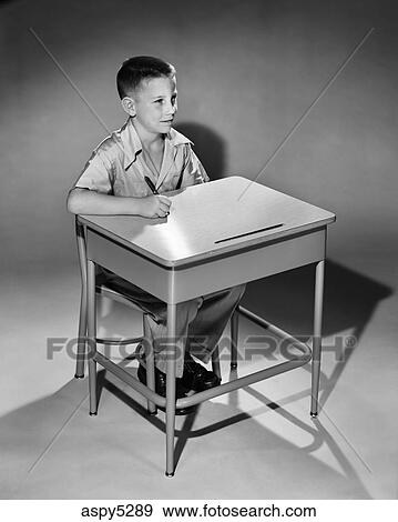 1950s Young Boy Holding Pen Sitting At Elementary School Desk