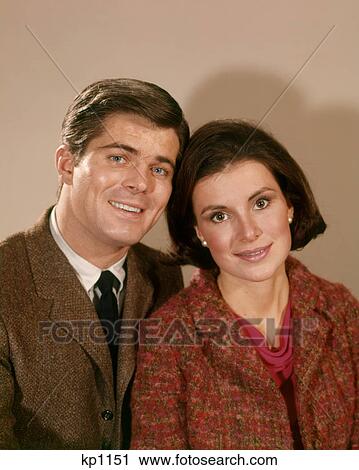Stock Image - 1960s 1960s SMILING PORTRAIT OF BRUNETTE COUPLE LOOKING AT CAMERA. Fotosearch