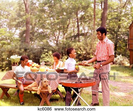 Stock Photograph - 1960S 1970S African American Family Backyard Bar-B-Que Mother Father Son And Daughter Outdoor. Fotosearch