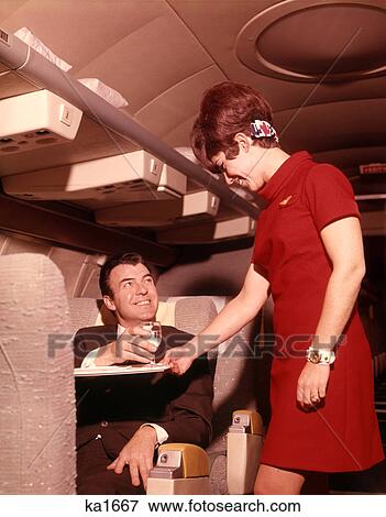 1960s 1970s AIRPLANE PLANE STEWARDESS SERVING BUSINESS MAN DRINK WINE WOMAN COMMERCIAL AIR TRAVEL View Large Photo Image Stock Photo - 1960s 1970s AIRPLANE PLANE STEWARDESS SERVING BUSINESS MAN DRINK WINE WOMAN COMMERCIAL AIR TRAVEL. Fotosearch