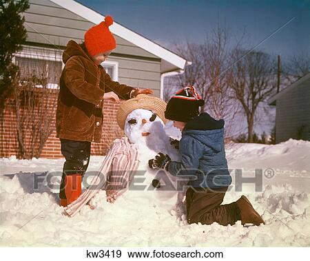 1960s 1970s BOY AND GIRL BROTHER AND SISTER MAKING SNOW MAN IN SUBURBAN HOUSE FRONT YARD View Large Photo Image Stock Photo - 1960s 1970s BOY AND GIRL BROTHER AND SISTER MAKING SNOW MAN IN SUBURBAN HOUSE FRONT YARD. Fotosearch