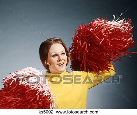 Stock Image - 1960s 1970s CHEERLEADER YELLOW TURTLENECK SWEATER RED WHITE POMPOMS CHEERING. Fotosearch