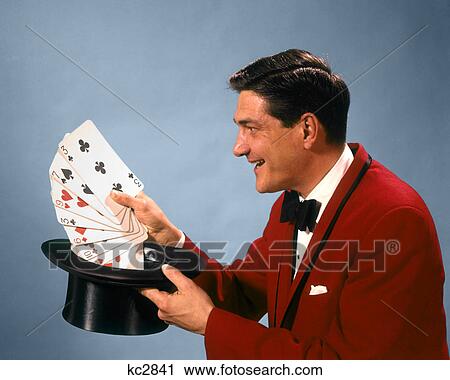 1960s 1970s MAN MAGICIAN RED SUIT BOW TIE PULLING OVERSIZE PLAYING CARDS OUT OF TOP HAT View Large Photo Image Stock Image - 1960s 1970s MAN MAGICIAN RED SUIT BOW TIE PULLING OVERSIZE PLAYING CARDS OUT OF TOP HAT. Fotosearch