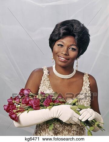 1960s 1970s SMILING AFRICAN AMERICAN WOMAN IN PEARL BEADED EVENING DRESS LONG WHITE GLOVES HOLDING RED ROSES LOOKING AT CAMERA View Large Photo Image Stock Image - 1960s 1970s SMILING AFRICAN AMERICAN WOMAN IN PEARL BEADED EVENING DRESS LONG WHITE GLOVES HOLDING RED ROSES LOOKING AT CAMERA. Fotosearch