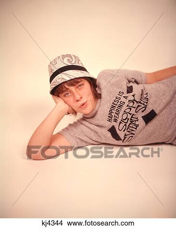 1960s 1970s TEEN GIRL MOD PRINT HAT LYING DOWN LEANING HEAD ON HAND WEARING GRAY SLOGAN SWEATSHIRT LOOKING AT CAMERA View Large Photo Image Picture - 1960s 1970s TEEN GIRL MOD PRINT HAT LYING DOWN LEANING HEAD ON HAND WEARING GRAY SLOGAN SWEATSHIRT LOOKING AT CAMERA. Fotosearch