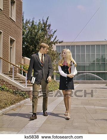 1960s 1970s YOUNG ADULT STUDENT COUPLE WALKING SIDE BY SIDE ON CAMPUS GIRL IN MINIDRESS BOY IN SUIT TIE View Large Photo Image Stock Photo - 1960s 1970s YOUNG ADULT STUDENT COUPLE WALKING SIDE BY SIDE ON CAMPUS GIRL IN MINIDRESS BOY IN SUIT TIE. Fotosearch