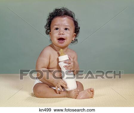 1960s AFRICAN AMERICAN BABY SMILING HOLDING BOTTLE View Large Photo Image Stock Photo - 1960s AFRICAN AMERICAN BABY SMILING HOLDING BOTTLE. Fotosearch