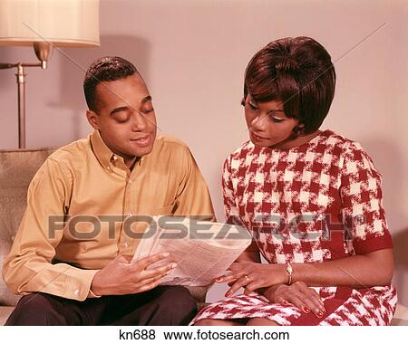 1960s AFRICAN AMERICAN COUPLE HUSBAND POINTING OUT NEWSPAPER ARTICLE TO WIFE View Large Photo Image Stock Photo - 1960s AFRICAN AMERICAN COUPLE HUSBAND POINTING OUT NEWSPAPER ARTICLE TO WIFE. Fotosearch
