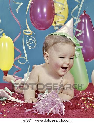 1960s BABY GIRL LAUGHING WEARING PARTY HAT AMID STREAMERS AND BALLOONS View Large Photo Image Picture - 1960s BABY GIRL LAUGHING WEARING PARTY HAT AMID STREAMERS AND BALLOONS. Fotosearch