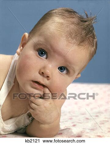 Stock Image - 1960s BABY PORTRAIT SERIOUS FACE EXPRESSION THOUGHTFUL PENSIVE FINGER CHIN MOUTH THINKING. Fotosearch