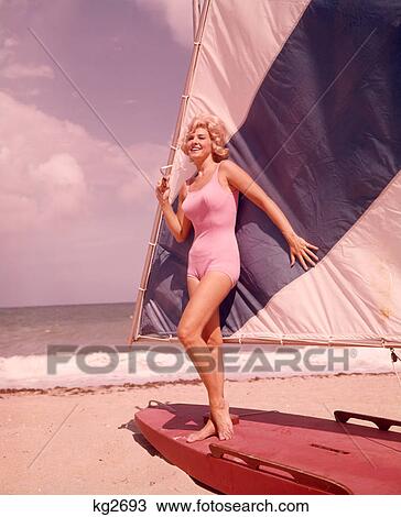 1960s BLOND WOMAN BEAUTY IN PINK SWIM WEAR BATHING SUIT POSED ON BLUE WHITE SAIL BOAT SAILFISH BOAT ON SUMMER SEASHORE BEACH View Large Photo Image Stock Image - 1960s BLOND WOMAN BEAUTY IN PINK SWIM WEAR BATHING SUIT POSED ON BLUE WHITE SAIL BOAT SAILFISH BOAT ON SUMMER SEASHORE BEACH. Fotosearch