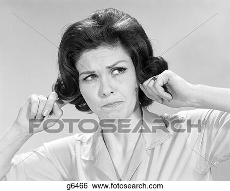 Stock Photograph - 1960s BRUNETTE WOMAN STICKING FINGERS INTO HER EARS. Fotosearch