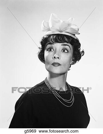 1960s BRUNETTE WOMAN WITH WIDE EYED EXPRESSION WEARING SILLY HAT hous View Large Photo Image Stock Photo - 1960s BRUNETTE WOMAN WITH WIDE EYED EXPRESSION WEARING SILLY HAT hous. Fotosearch