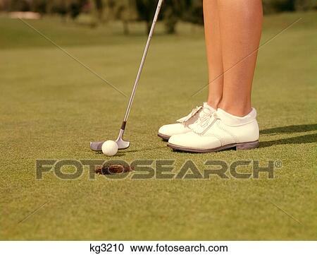 1960s CLOSE-UP OF FEMALE LEGS WEARING WHITE GOLF SHOES AND CLUB PUTTER ABOUT TO STROKE BALL INTO HOLE CUP ON THE GREEN View Large Photo Image Stock Image - 1960s CLOSE-UP OF FEMALE LEGS WEARING WHITE GOLF SHOES AND CLUB PUTTER ABOUT TO STROKE BALL INTO HOLE CUP ON THE GREEN. Fotosearch
