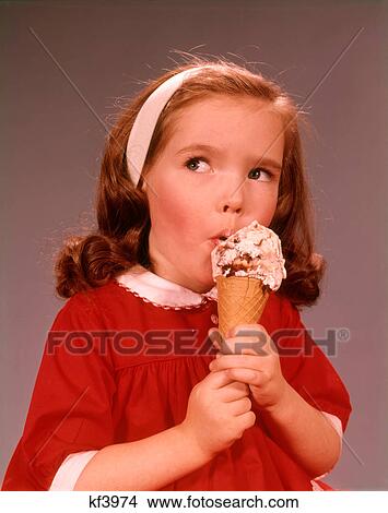 Picture - 1960s CUTE EXPRESSION BRUNETTE LITTLE GIRL WEARING A RED DRESS EATING ICE CREAM CONE. Fotosearch