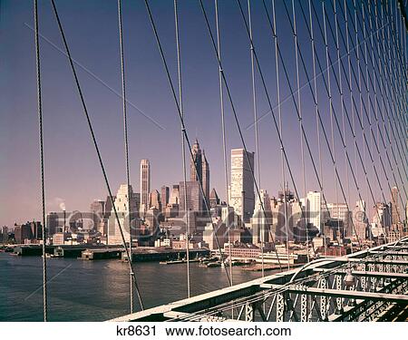 1960s DOWNTOWN MANHATTAN FINANCIAL AREA SKYLINE SEEN THROUGH BROOKLYN BRIDGE SUSPENSION CABLES WTC SEEN UNDER CONSTRUCTION View Large Photo Image Stock Image - 1960s DOWNTOWN MANHATTAN FINANCIAL AREA SKYLINE SEEN THROUGH BROOKLYN BRIDGE SUSPENSION CABLES WTC SEEN UNDER CONSTRUCTION. Fotosearch