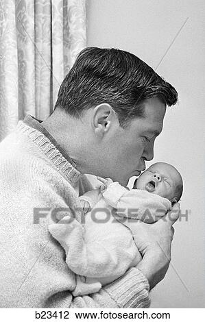 Stock Image - 1960s FATHER HOLDING AND KISSING HIS INFANT BABY SON. Fotosearch
