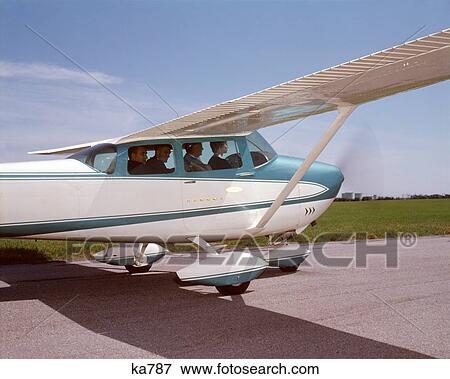 Stock Photo - 1960s FOUR BUSINESSMEN MEN EXECUTIVES SITTING IN CESSNA SKYLANE PRIVATE PROPELLOR AIRPLANE TAXING ON TARMAC RUNWAY. Fotosearch