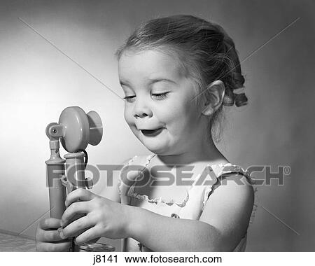 1960S Girl Both Hands Holding A Toy Candle Stick Phone Funny Facial Expression View Large Photo Image Stock Image - 1960S Girl Both Hands Holding A Toy Candle Stick Phone Funny Facial Expression. Fotosearch
