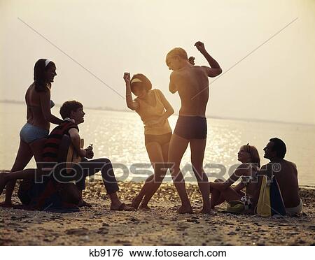 1960S Group Of Young Couples Playing Guitar And Dancing Sunset Beach Party View Large Photo Image Stock Photograph - 1960S Group Of Young Couples Playing Guitar And Dancing Sunset Beach Party. Fotosearch