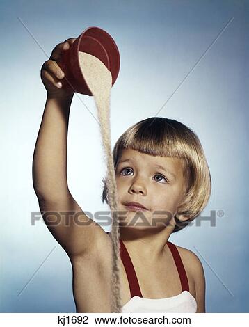 1960s LITTLE BLOND GIRL WEARING BATHING SUIT PLAYING POURING SEASHORE BEACH SAND FROM RED PLASTIC TOY PAIL View Large Photo Image Stock Image - 1960s LITTLE BLOND GIRL WEARING BATHING SUIT PLAYING POURING SEASHORE BEACH SAND FROM RED PLASTIC TOY PAIL. Fotosearch