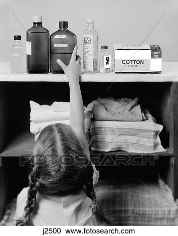 Stock Image - 1960S Little Girl Reaching To Top Shelf For Bottle Of Poison . Fotosearch