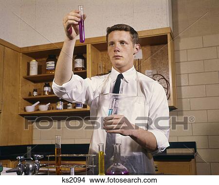 Picture - 1960s MALE HIGH SCHOOL TEENAGE STUDENT IN CHEMISTRY LABORATORY HOLDING TEST TUBES. Fotosearch