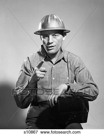Stock Photo - 1960S Man Hard Hat Arm Over Tin Lunchbox Speaking Pointing Finger. Fotosearch