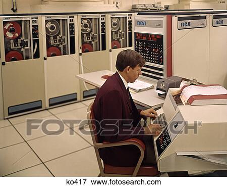 1960s MAN PROGRAMMER ENTERING DATA ON SYSTEM CONSOLE KEYBOARD IN COMPUTER ROOM WITH MAINFRAME TAPE STORAGE DRIVE MACHINES View Large Photo Image Stock Photo - 1960s MAN PROGRAMMER ENTERING DATA ON SYSTEM CONSOLE KEYBOARD IN COMPUTER ROOM WITH MAINFRAME TAPE STORAGE DRIVE MACHINES. Fotosearch