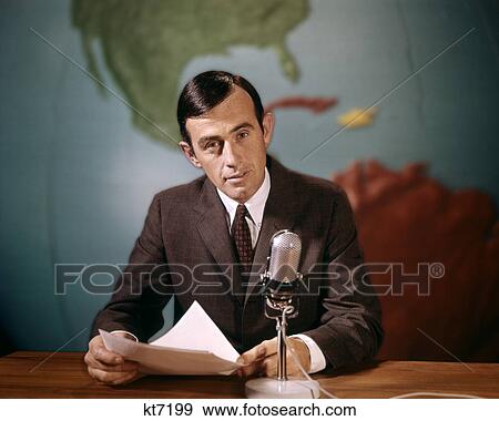 Stock Photo - 1960s NEWSMAN READING NEWS FROM PAPERS SPEAKING INTO MICROPHONE LOOKING AT CAMERA. Fotosearch