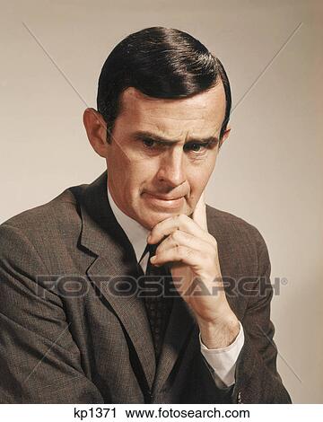 1960s PORTRAIT MAN WITH SERIOUS FACIAL EXPRESSION HAND AT CHIN HEAD DOWN LOOKING AT CAMERA View Large Photo Image Stock Image - 1960s PORTRAIT MAN WITH SERIOUS FACIAL EXPRESSION HAND AT CHIN HEAD DOWN LOOKING AT CAMERA. Fotosearch
