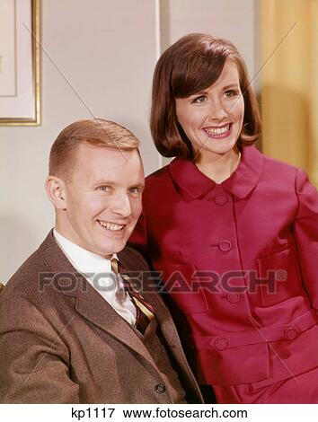 1960s PORTRAIT SMILING YOUNG COUPLE MAN IN BUSINESS SUIT WOMAN WEARING RED DRESS View Large Photo Image Stock Photo - 1960s PORTRAIT SMILING YOUNG COUPLE MAN IN BUSINESS SUIT WOMAN WEARING RED DRESS. Fotosearch