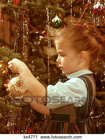 1960s PROFILE SERIOUS LITTLE GIRL HANGING GLASS ORNAMENT ON CHRISTMAS TREE BRANCH View Large Photo Image Stock Image - 1960s PROFILE SERIOUS LITTLE GIRL HANGING GLASS ORNAMENT ON CHRISTMAS TREE BRANCH. Fotosearch