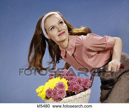 1960s REDHEAD WOMAN RIDING BICYCLE WITH BASKET FULL OF AUTUMN FLOWERS View Large Photo Image Stock Image - 1960s REDHEAD WOMAN RIDING BICYCLE WITH BASKET FULL OF AUTUMN FLOWERS. Fotosearch
