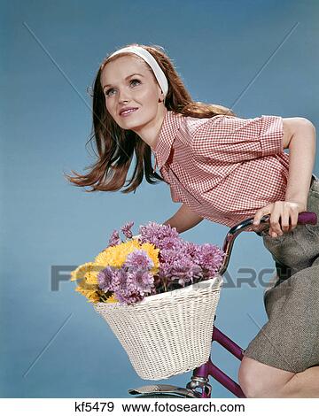1960s REDHEAD WOMAN RIDING BICYCLE WITH BASKET FULL OF AUTUMN FLOWERS View Large Photo Image Stock Photo - 1960s REDHEAD WOMAN RIDING BICYCLE WITH BASKET FULL OF AUTUMN FLOWERS. Fotosearch