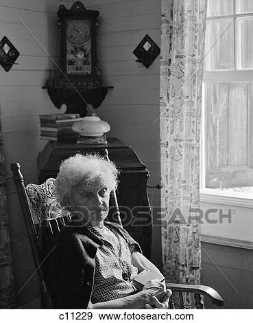 1960S Sad Lonely Elderly Woman Sitting In Rocking Chair Illuminated By Window Light View Large Photo Image Stock Photo - 1960S Sad Lonely Elderly Woman Sitting In Rocking Chair Illuminated By Window Light. Fotosearch