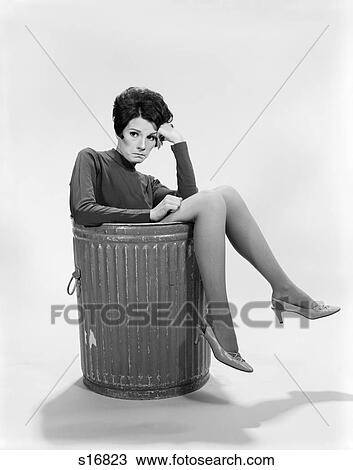 1960s SAD SERIOUS WORRIED EXPRESSION BRUNETTE WOMAN SITTING IN METAL TRASH CAN LEGS OVER SIDE IN A JAM LOOKING AT CAMERA View Large Photo Image Stock Image - 1960s SAD SERIOUS WORRIED EXPRESSION BRUNETTE WOMAN SITTING IN METAL TRASH CAN LEGS OVER SIDE IN A JAM LOOKING AT CAMERA. Fotosearch