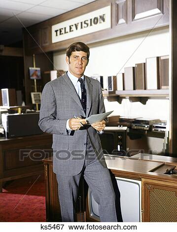 1960s SALESMAN STANDING IN TELEVISION SECTION OF DEPARTMENT STORE LOOKING AT CAMERA View Large Photo Image Stock Photo - 1960s SALESMAN STANDING IN TELEVISION SECTION OF DEPARTMENT STORE LOOKING AT CAMERA. Fotosearch