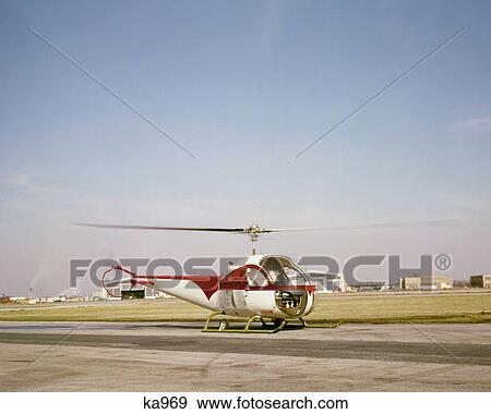 1960s SMALL RED WHITE HELICOPTER ON HELIPORT RUNWAY TARMAC View Large Photo Image Stock Photo - 1960s SMALL RED WHITE HELICOPTER ON HELIPORT RUNWAY TARMAC. Fotosearch