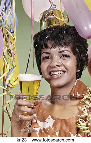1960S Smiling African American Woman Party Hat Streamers Balloons Toasting Pilsner Glass Of Beer View Large Photo Image Stock Image - 1960S Smiling African American Woman Party Hat Streamers Balloons Toasting Pilsner Glass Of Beer. Fotosearch