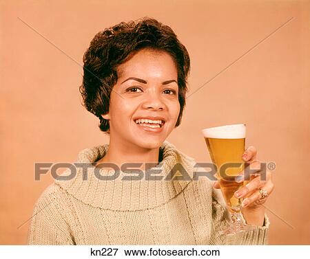 1960s SMILING AFRICAN AMERICAN WOMAN LOOKING AT CAMERA HOLDING GLASS OF BEER View Large Photo Image Stock Photo - 1960s SMILING AFRICAN AMERICAN WOMAN LOOKING AT CAMERA HOLDING GLASS OF BEER. Fotosearch