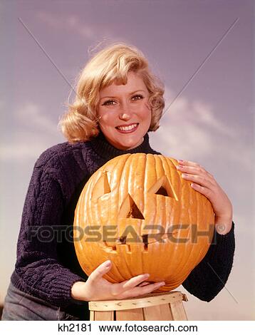 1960s SMILING BLOND WOMAN HOLDING JACK-O-LANTERN CARVED PUMPKIN LOOKING AT CAMERA View Large Photo Image Stock Image - 1960s SMILING BLOND WOMAN HOLDING JACK-O-LANTERN CARVED PUMPKIN LOOKING AT CAMERA. Fotosearch