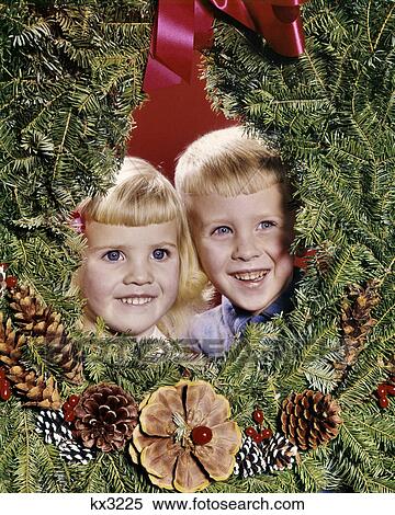 1960s SMILING BLONDE BOY AND GIRL BROTHER AND SISTER PEEKING OUT FROM CENTER OF CHRISTMAS WREATH View Large Photo Image Stock Photography - 1960s SMILING BLONDE BOY AND GIRL BROTHER AND SISTER PEEKING OUT FROM CENTER OF CHRISTMAS WREATH. Fotosearch
